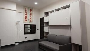 A modern room with a grey sofa, white cabinets, and recessed ceiling lights. - Sofia e la città delle meraviglie (Naples)