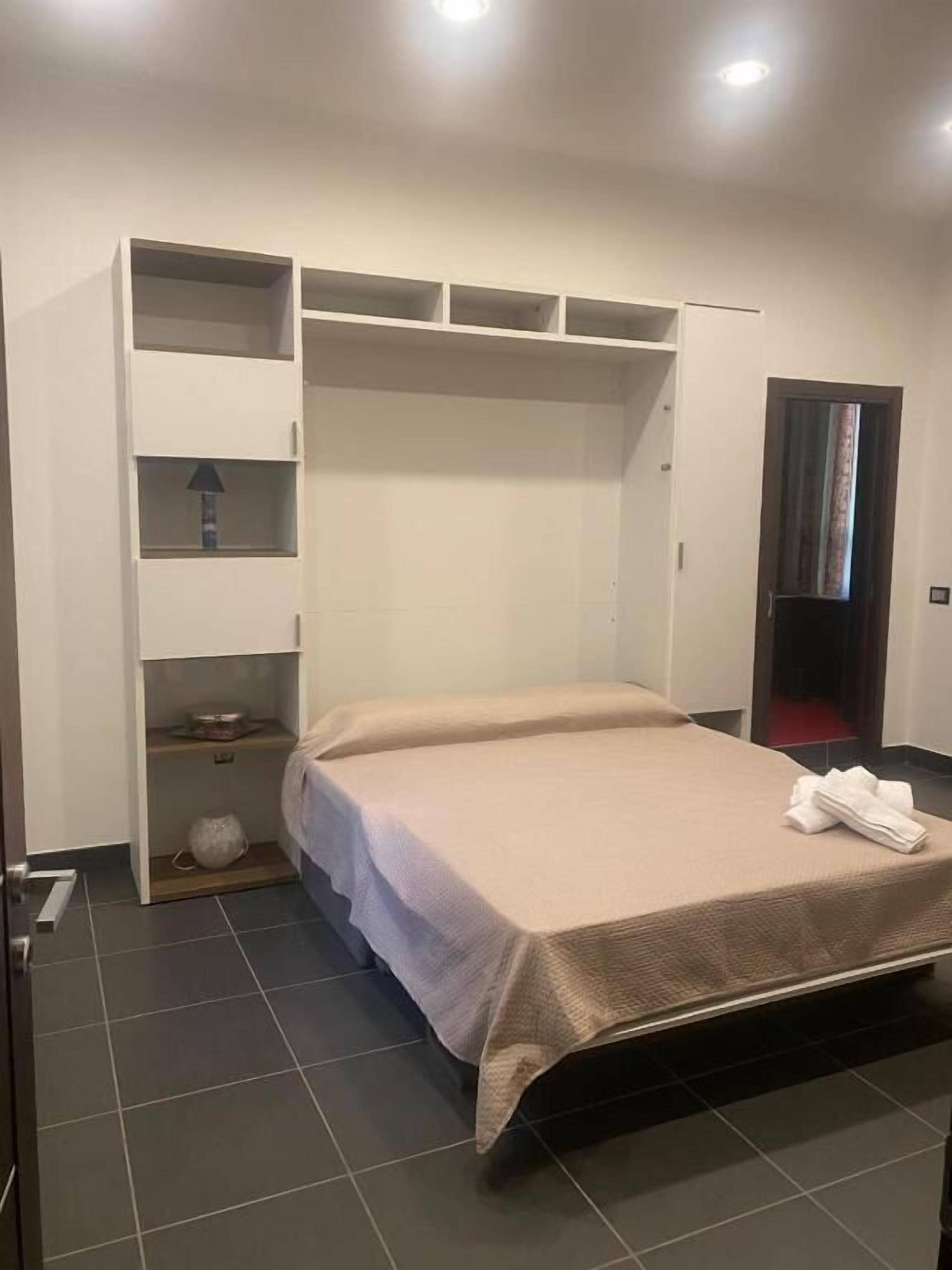 Une chambre à coucher avec un lit, une armoire et une petite table avec une lampe.