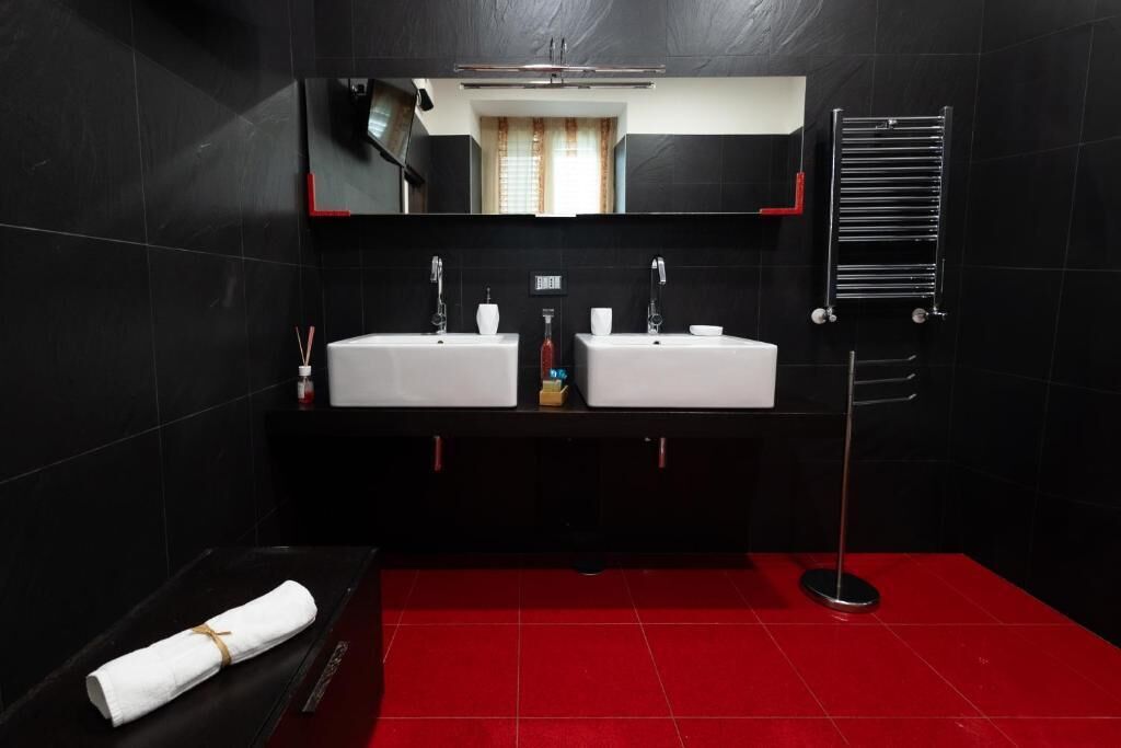 A modern bathroom with two sinks, a large mirror, and a red floor.