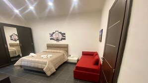 A bedroom with a bed, a red sofa, a nightstand, a mirror, and a wardrobe. - Sofia e la città delle meraviglie (Naples)