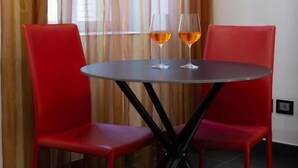 A room with a round table, two red chairs, and two glasses of wine on the table. - Sofia e la città delle meraviglie (Naples)