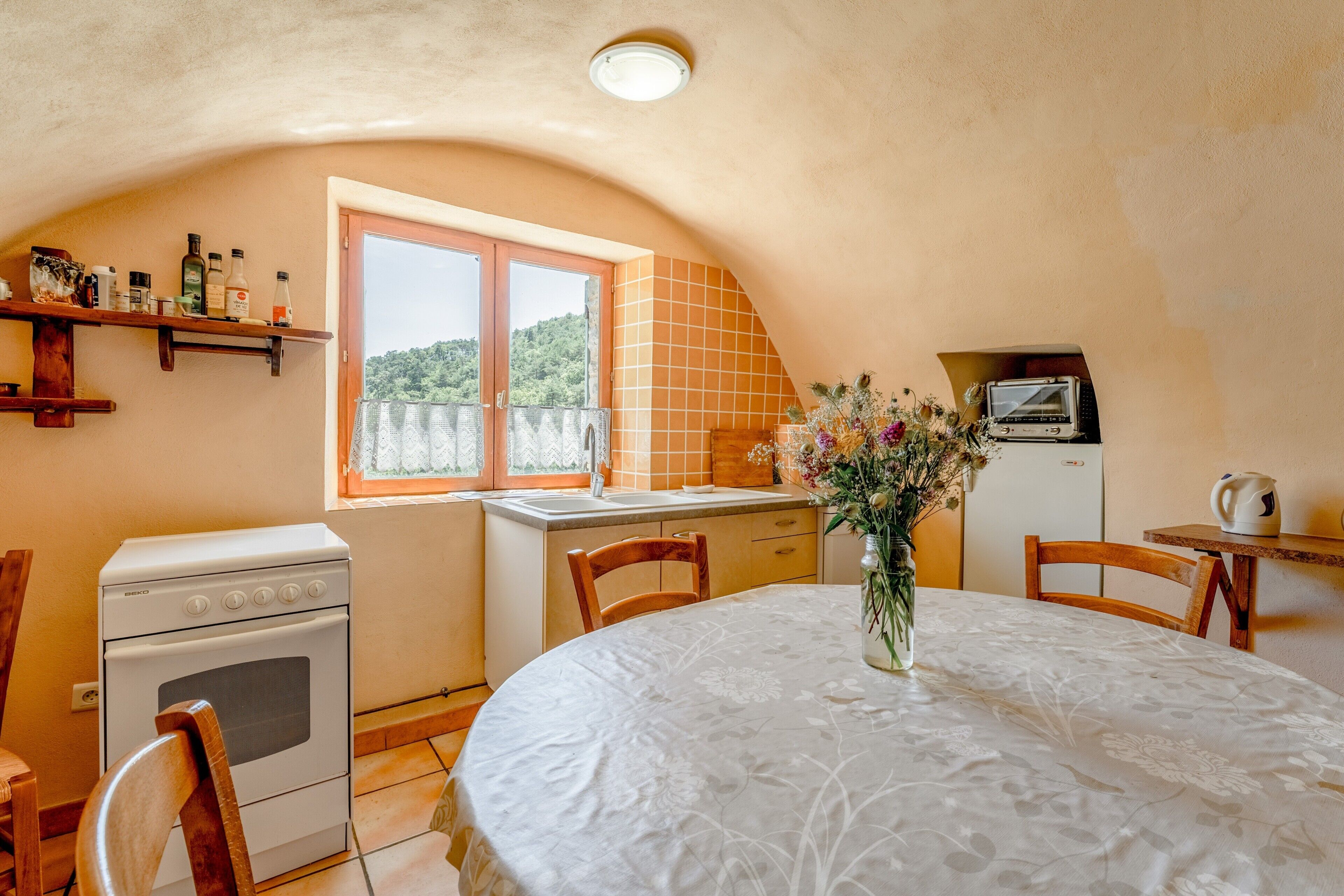 A kitchen with a stove, oven, and a window overlooking greenery.