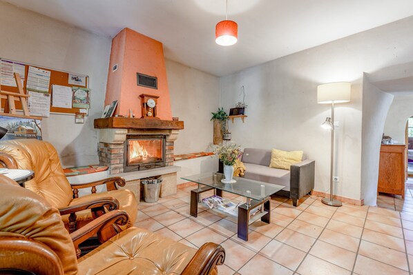 A living room with a fireplace, leather furniture, a glass coffee table, and a floor lamp.