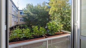 A balcony with potted plants, a view of a building, and a clear sky. - Auditorium Enchanting Apartment (Roma)