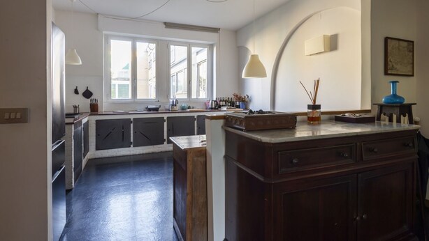 A kitchen with a central island, a window, and a hanging light fixture. - Auditorium Enchanting Apartment (Roma)