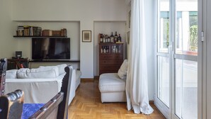 A living room with a sofa, a television, a bookshelf, and a sliding glass door. - Auditorium Enchanting Apartment (Roma)