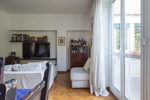 A living room with a sofa, a television, a bookshelf, and a sliding glass door. - Auditorium Enchanting Apartment (Roma)