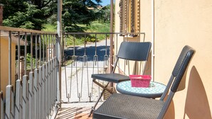 A balcony with a metal railing, two chairs, a small round table, and a pink container. - Casa Roda – Your Home by Lake Trasimeno, Between Umbria and Tuscany (Castiglione del Lago)