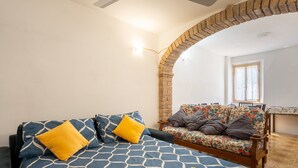 A bedroom with a bed, a sofa, a brick archway, and a window. - Casa Roda – Your Home by Lake Trasimeno, Between Umbria and Tuscany (Castiglione del Lago)