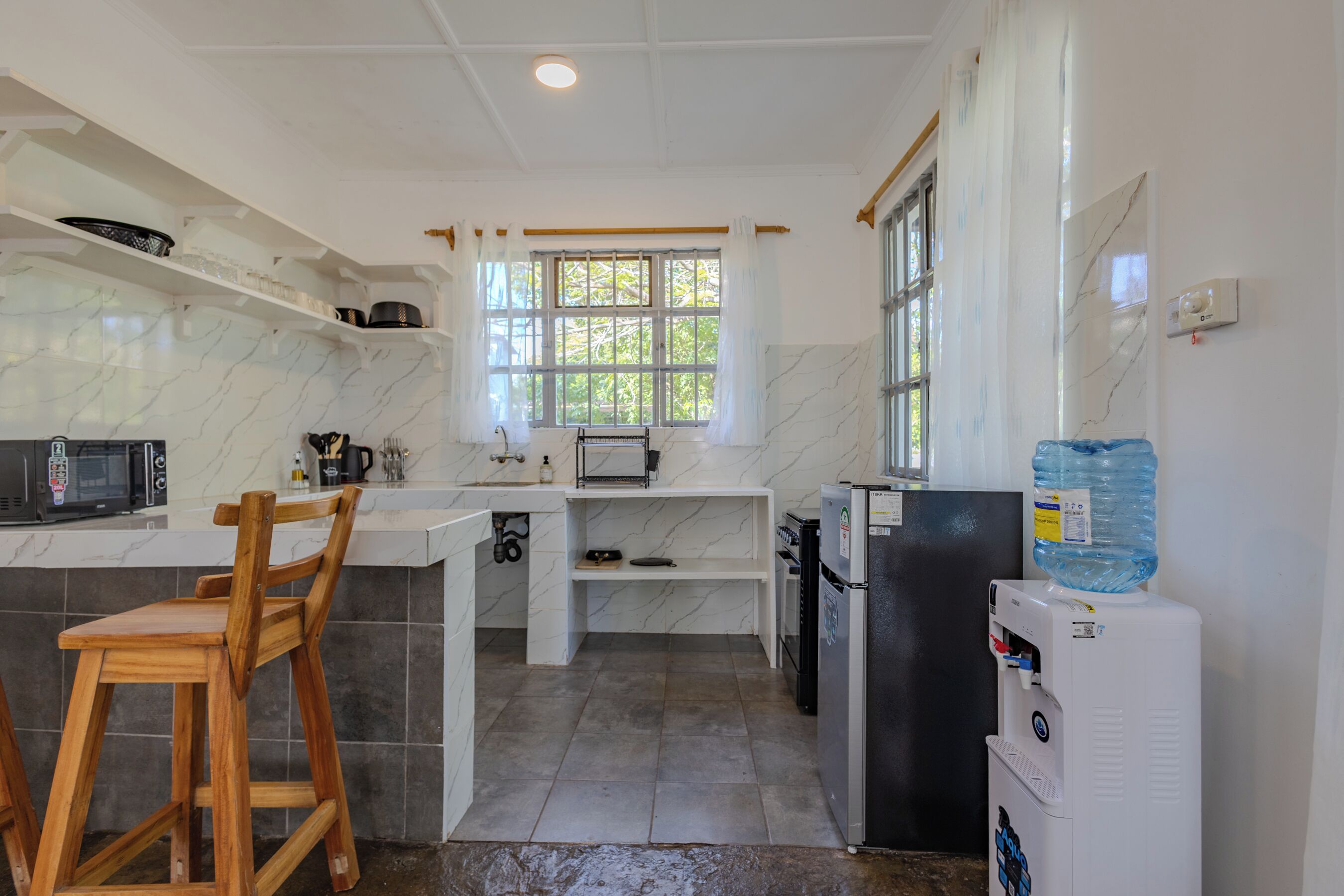 A compact kitchen with a microwave, toaster, and water dispenser.