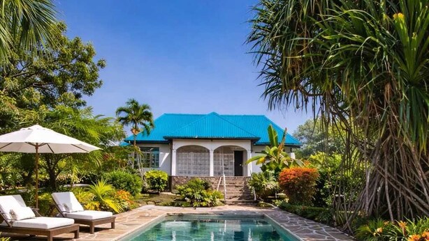 A clear swimming pool with lounge chairs and a house in the background. - AUREGI VILLAS (Diani Beach)