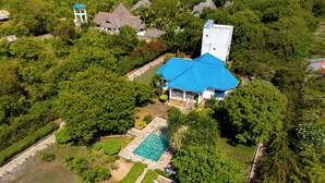 An aerial view of a property with a swimming pool, a gazebo, and a large tree. - AUREGI VILLAS (Diani Beach)