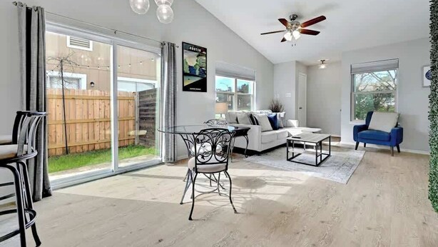 A spacious living room with a glass door leading to a backyard, a ceiling fan, and a large window. - South Austin Retreat: Pet-Friendly Townhouse (Austin)