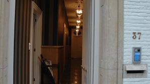 Entrada de un hotel con un mostrador de recepción, un buzón y un letrero con el número 37 en la pared.