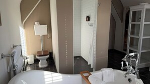 Un baño moderno con una bañera independiente, inodoro y zona de ducha.