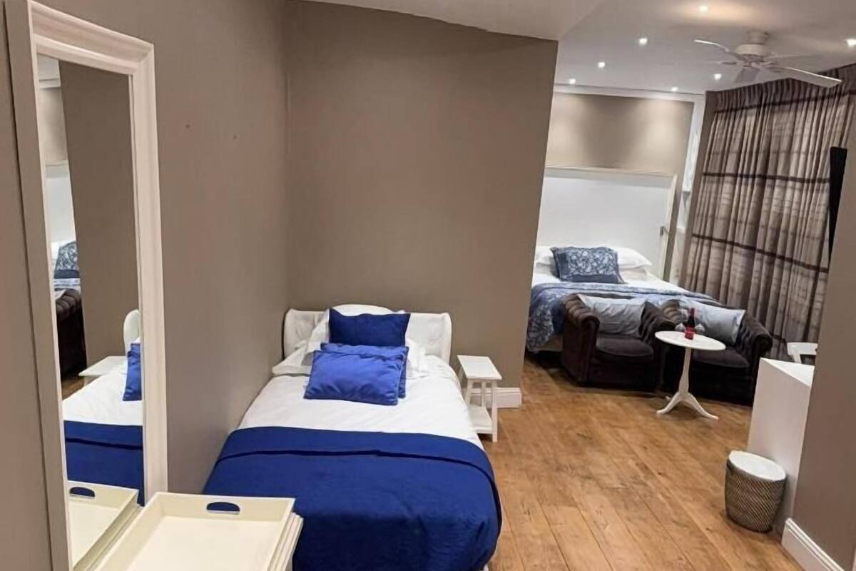 Een moderne hotelkamer met twee bedden, een tafeltje, een spiegel en een raam met gordijnen.