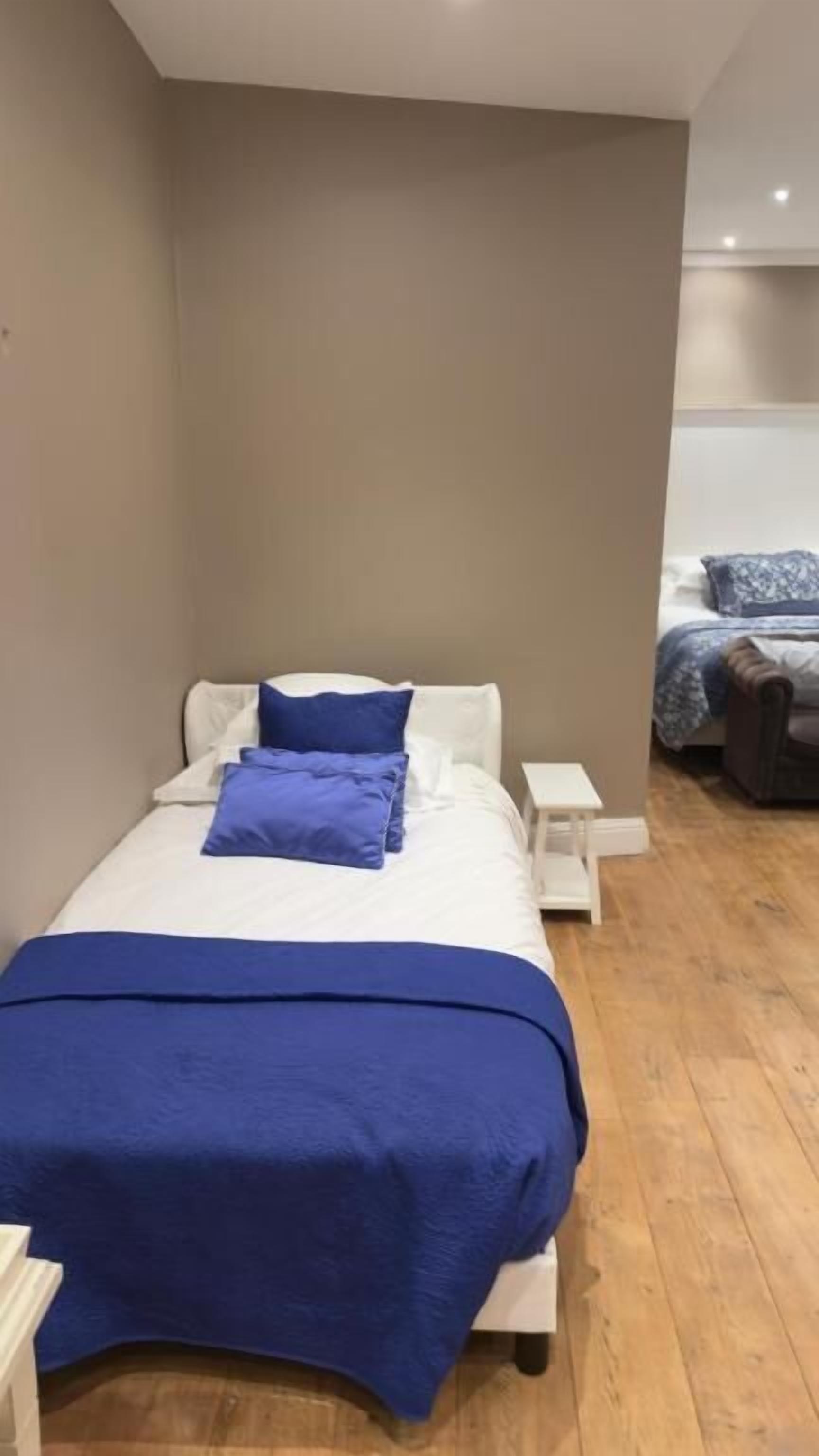 Ein Schlafzimmer mit einem Bett, zwei Kissen, einem Nachttisch und Holzboden.