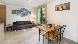 Un salon moderne comprenant un canapé, une table à manger et des chaises, une petite table d’appoint et un tableau accroché au mur.