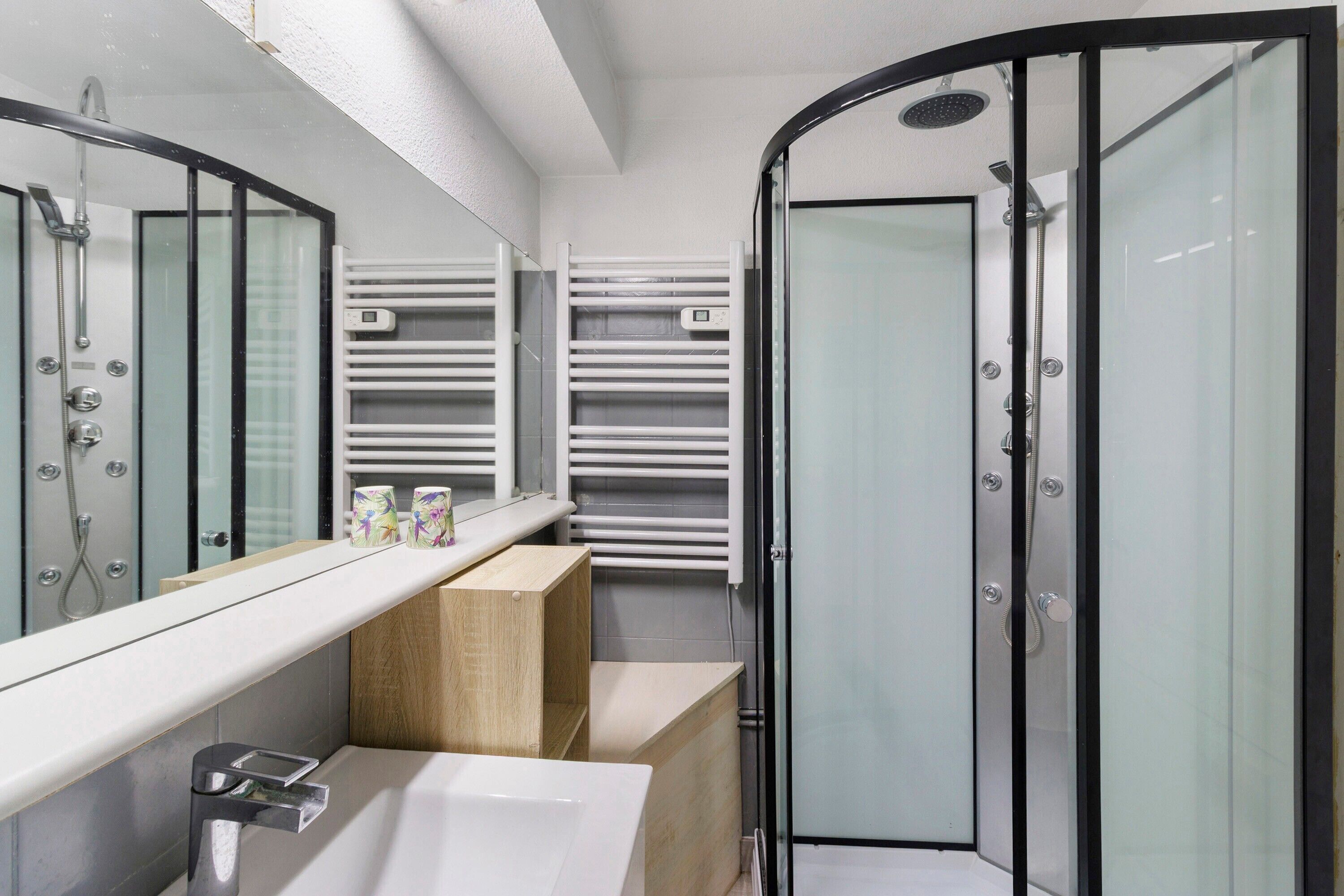 Une salle de bain moderne avec une douche à parois de verre, un lavabo blanc et un miroir.