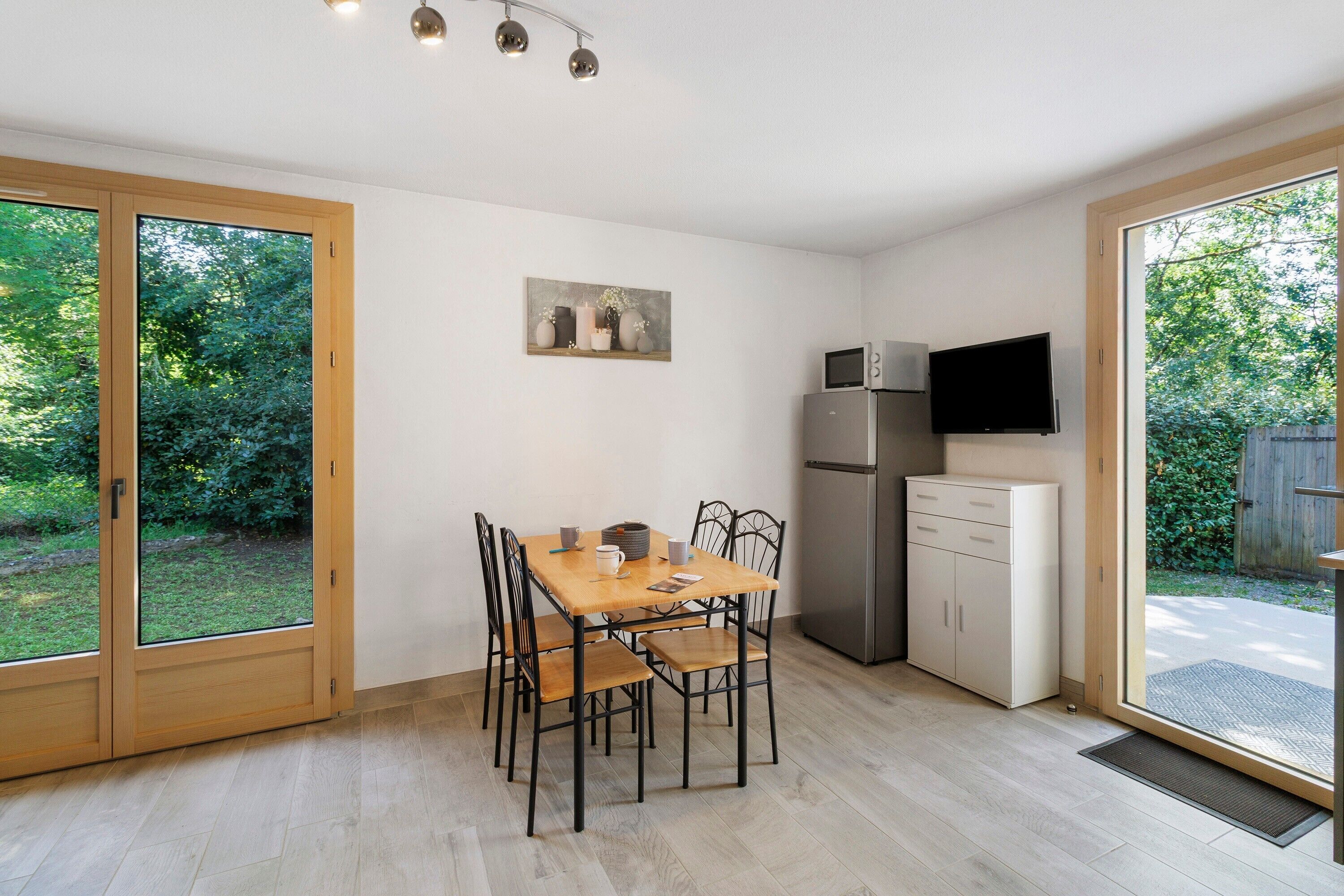 A kitchen with a dining table, chairs, a refrigerator, a microwave, and a TV.