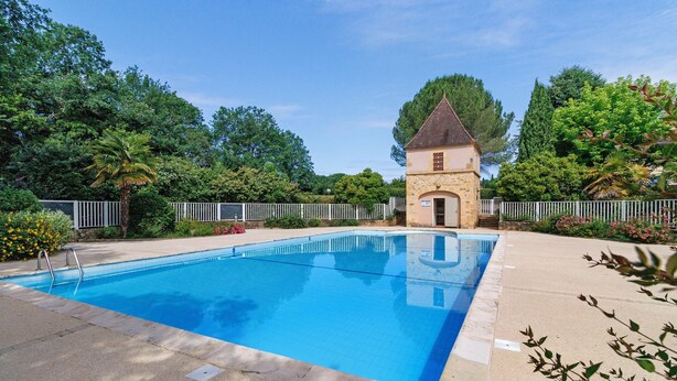 Une piscine avec un bâtiment en pierre en arrière-plan.