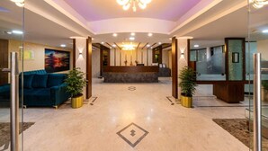 A hotel lobby with a reception desk, a blue sofa, and potted plants. - Midtown Suites  Marathahalli (Bengaluru)