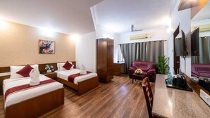 A hotel room with two beds, a sofa, a small table, and a TV. - Midtown Suites  Marathahalli (Bengaluru)
