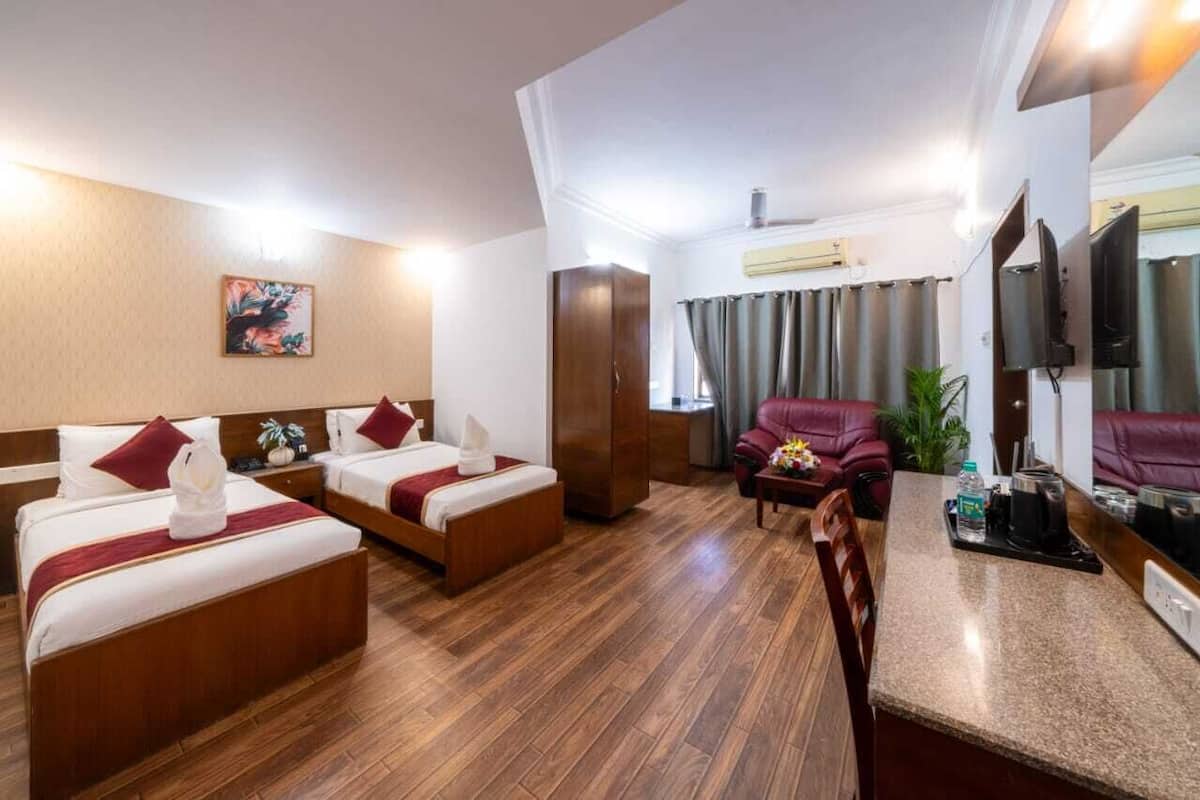 A hotel room with two beds, a sofa, a small table, and a TV.