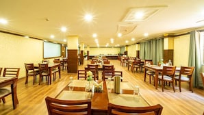 A spacious dining area with multiple tables and chairs, wooden flooring, and a high ceiling with recessed lighting. - Midtown Suites  Marathahalli (Bengaluru)