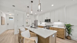 A modern kitchen with white cabinets, stainless steel appliances, and a central island with seating.