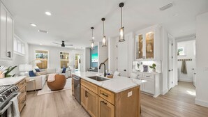A modern kitchen with wooden cabinets, a central island, and pendant lighting.