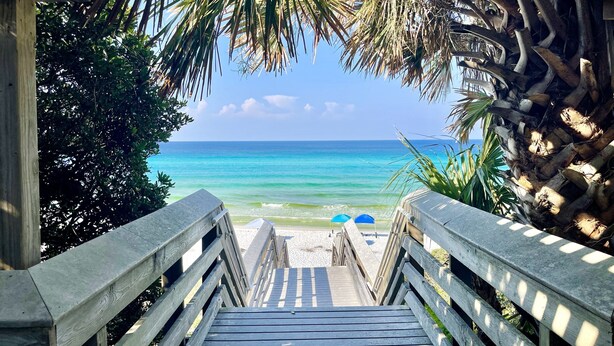 A wooden staircase leading to a beach with a clear view of the ocean.