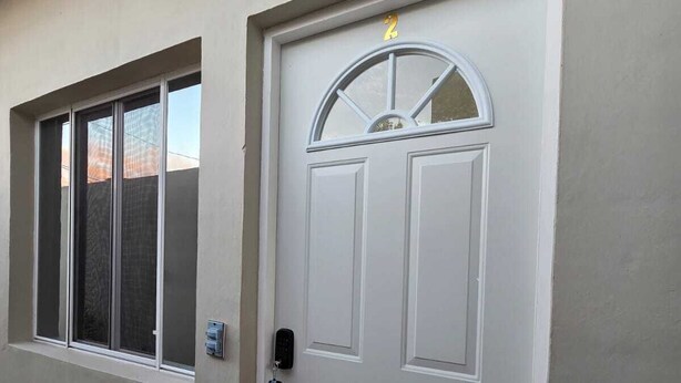 Puerta blanca con cerradura electrónica y un pequeño ventanal en la parte superior.
