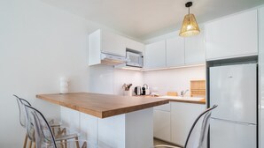 Eine moderne Küche mit weißen Schränken, einer Holz Arbeitsplatte, einer eingebauten Mikrowelle und einem Kühlschrank.