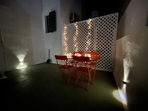 Ein Essbereich mit Tisch und Stühlen, einer dekorativen Gitterwand und einem Scheinwerfer auf dem Boden.