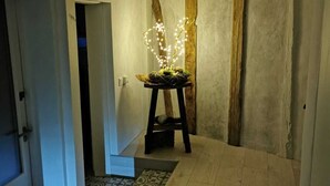 Un pasillo con piso de madera, un taburete pequeño con luces y una puerta a la izquierda.