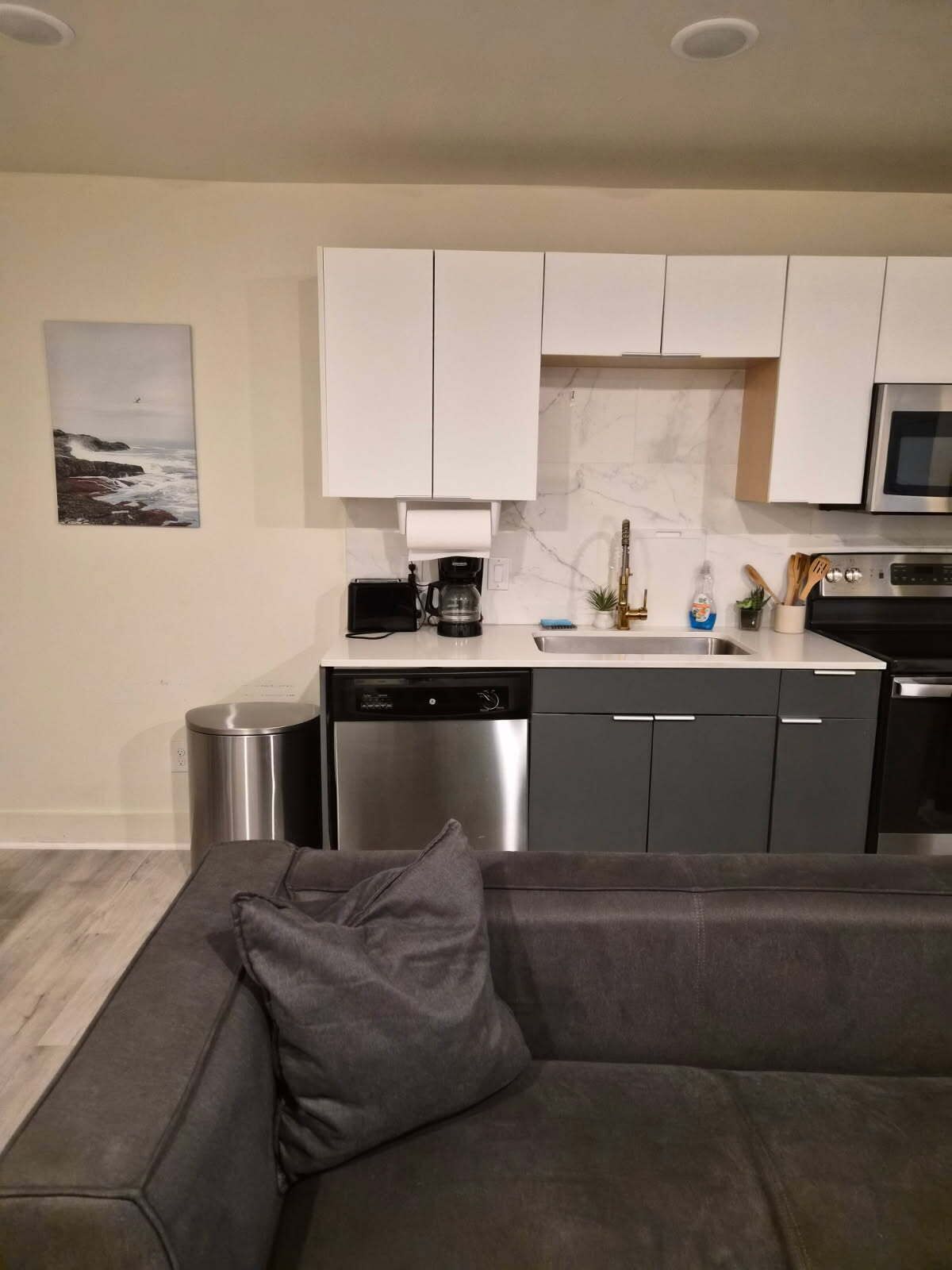 A modern kitchen with white cabinets, a stainless steel dishwasher, and a microwave.