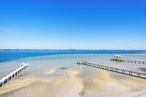 A beach with a pier extending into calm blue waters, a sandy shore, and a clear sky. - 🌞🌴Sound Views | Golf Cart | Community Pool | An Island in the Sun🌞🌴 (Navarre)