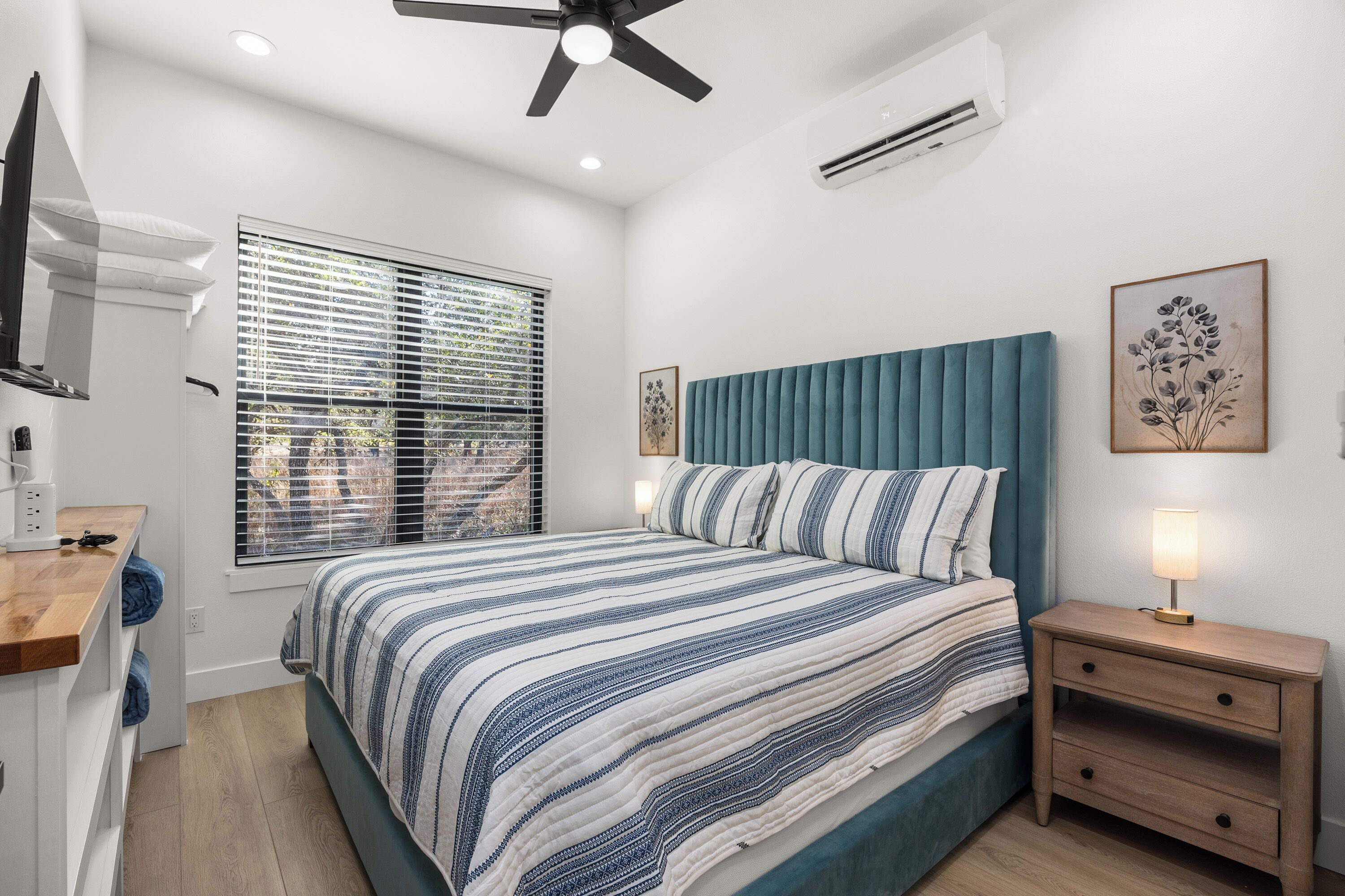 Una camera da letto con un letto, un comodino e una ventola a soffitto.