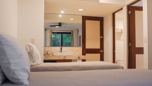 A hotel room with a bed, a bathroom with a sink, and a mirror. - Luxury Condo in PGA Golf Resort | Bahia Principe (Akumal)