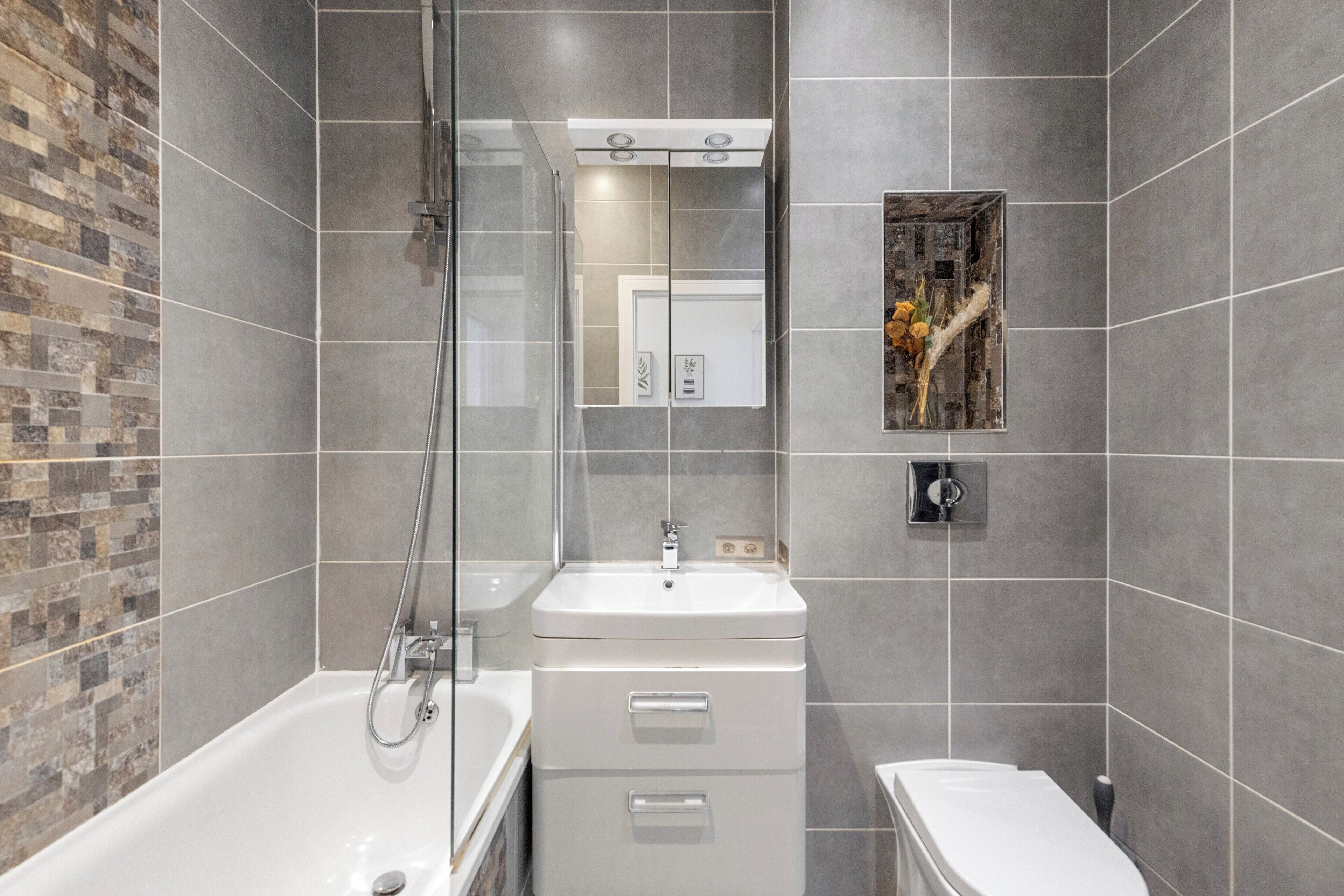 Ein modernes Badezimmer mit einer Duschkabine, einem weißen Waschbecken und einer Toilette.