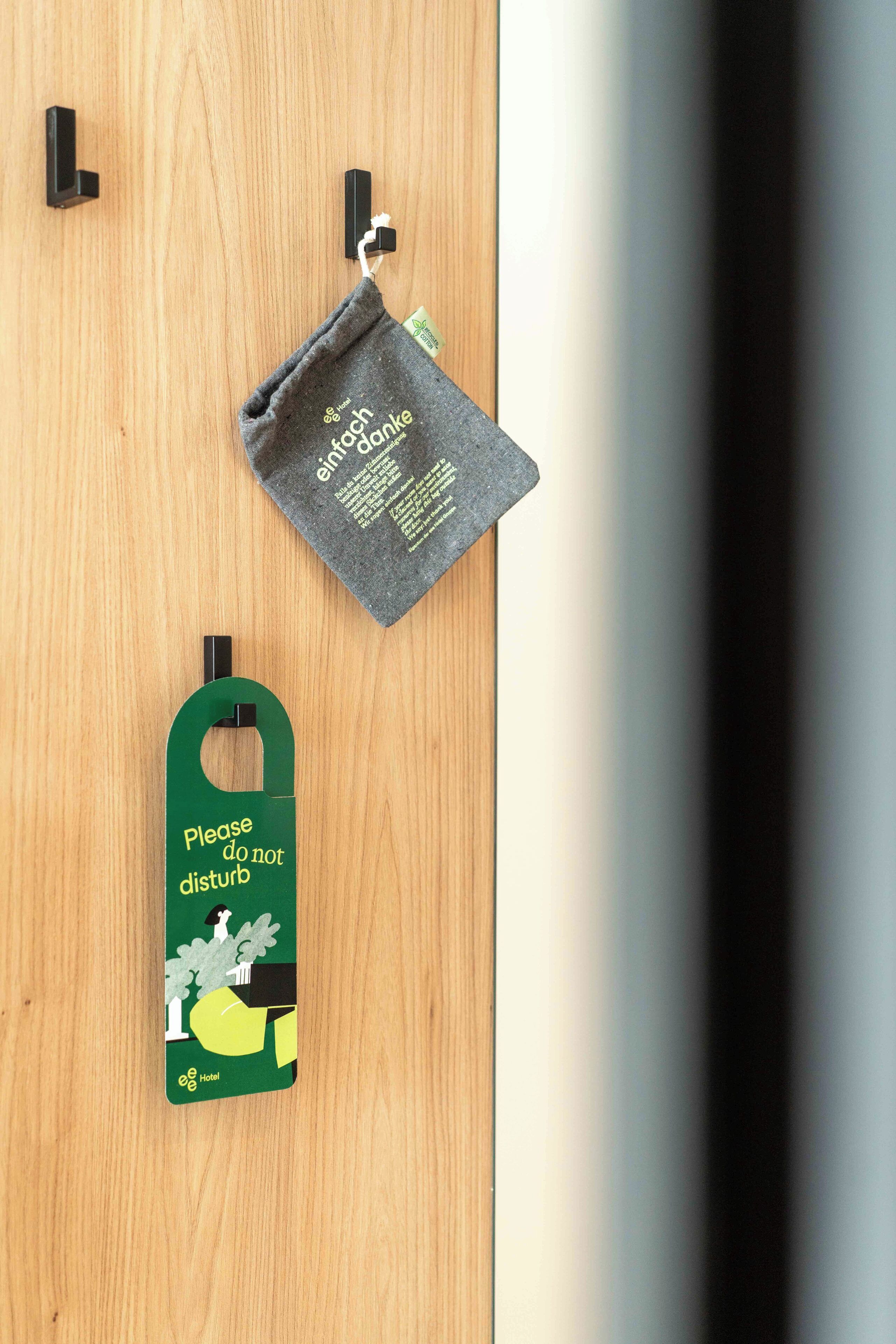 Una puerta de madera con una etiqueta de hotel verde y un paño gris colgado de ganchos.