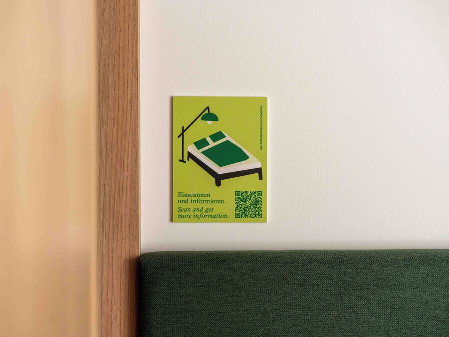 A green sign with a bed and a lamp, and a QR code on a white wall.