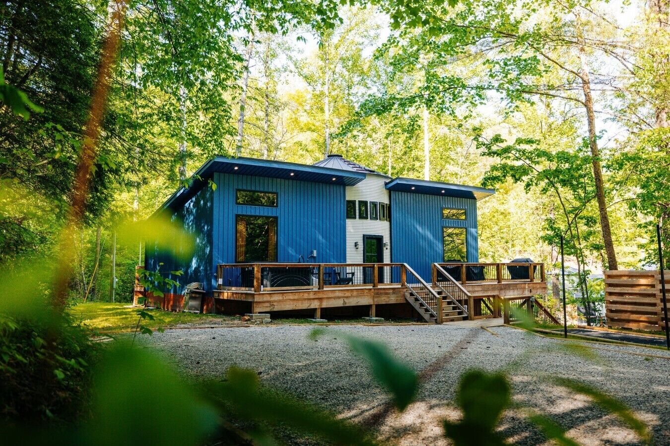 A blue cabin with a wooden deck and a staircase leading to the entrance.