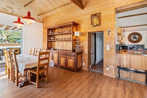 A wooden interior with a dining area, kitchen, and a view of the outdoors. - Tropical Escape in Dordogne (Le Fleix)