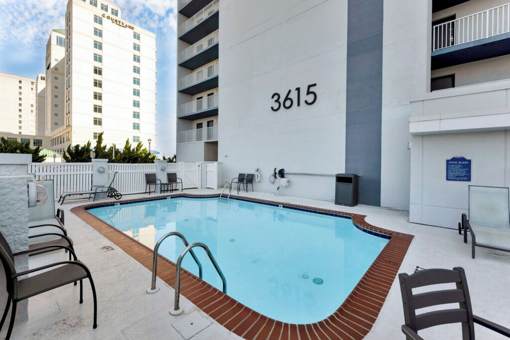 A swimming pool with a number '3615' on the wall, surrounded by outdoor seating and a fence.