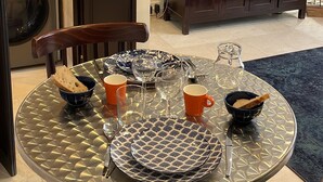 A dining area with a round table set for two, a microwave, a washing machine, and a TV in the background. - Paris TROCADERO, 5 mn from the TOUR EIFFEL apartment for 4 people (Paris)