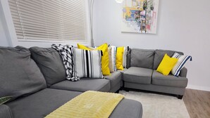 A modern living room with a grey sectional sofa, a yellow throw blanket, and a floor lamp.