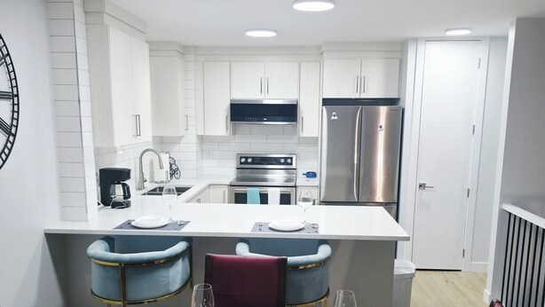 A modern kitchen with white cabinets, stainless steel appliances, and a central island.