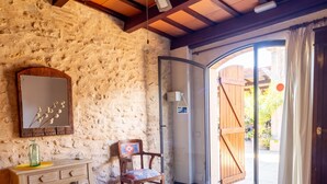 A room with a bed, a desk, a chair, a ceiling fan, and a door leading outside. - Masia Notari Casabona (Vilanova I la Geltru)